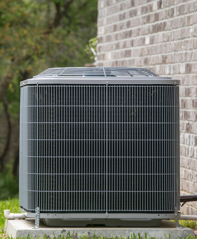 An outdoor air-conditioning condenser beside a residential wall