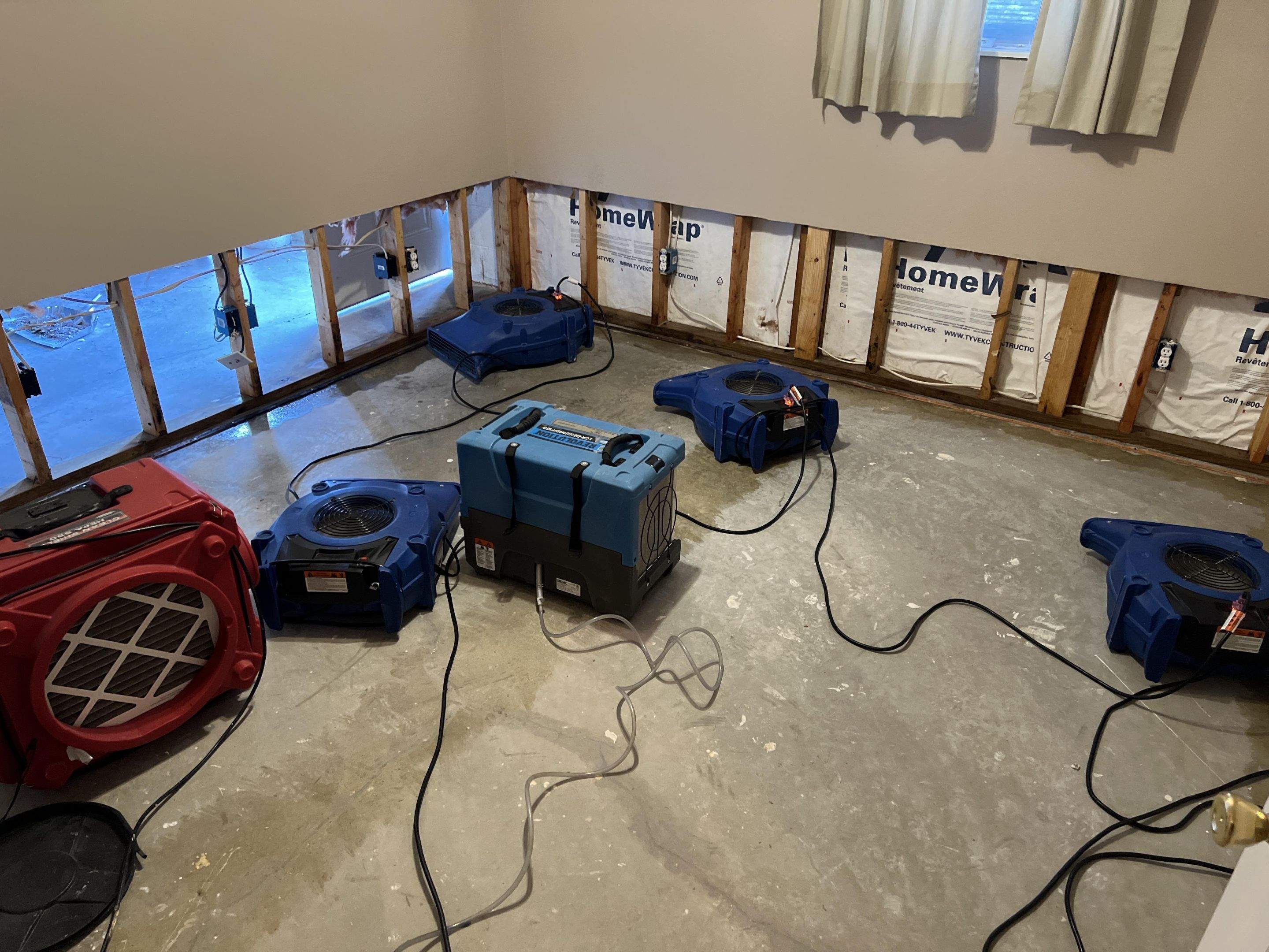 Drying fans and a dehumidifier positioned in a room after indoor water damage